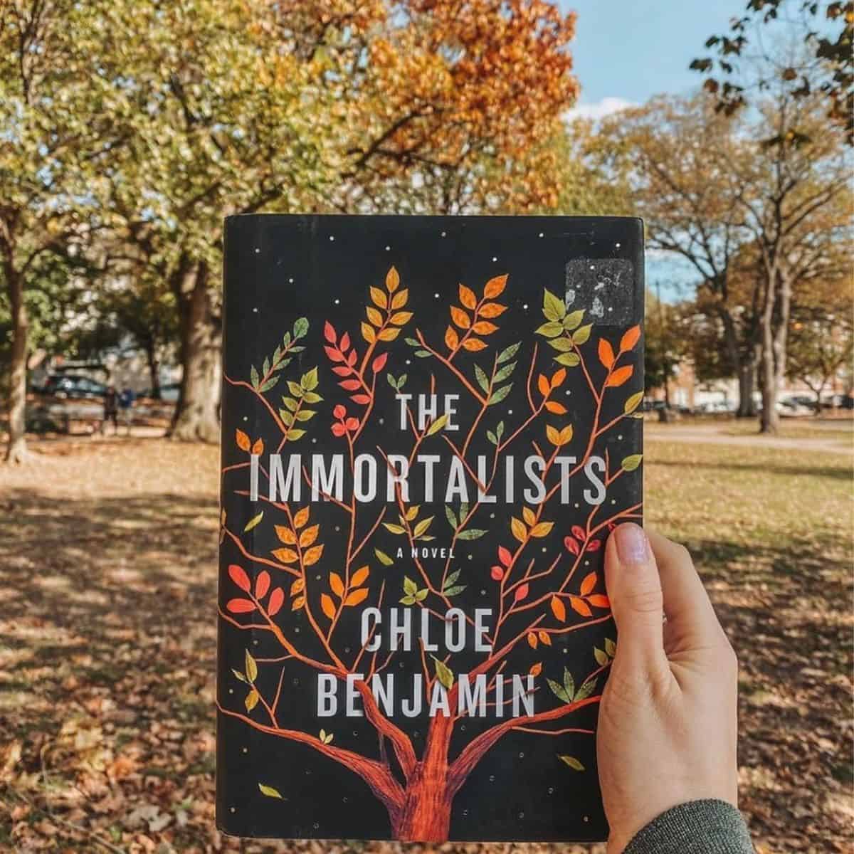 the immortalists by chloe benjamin in front of trees.