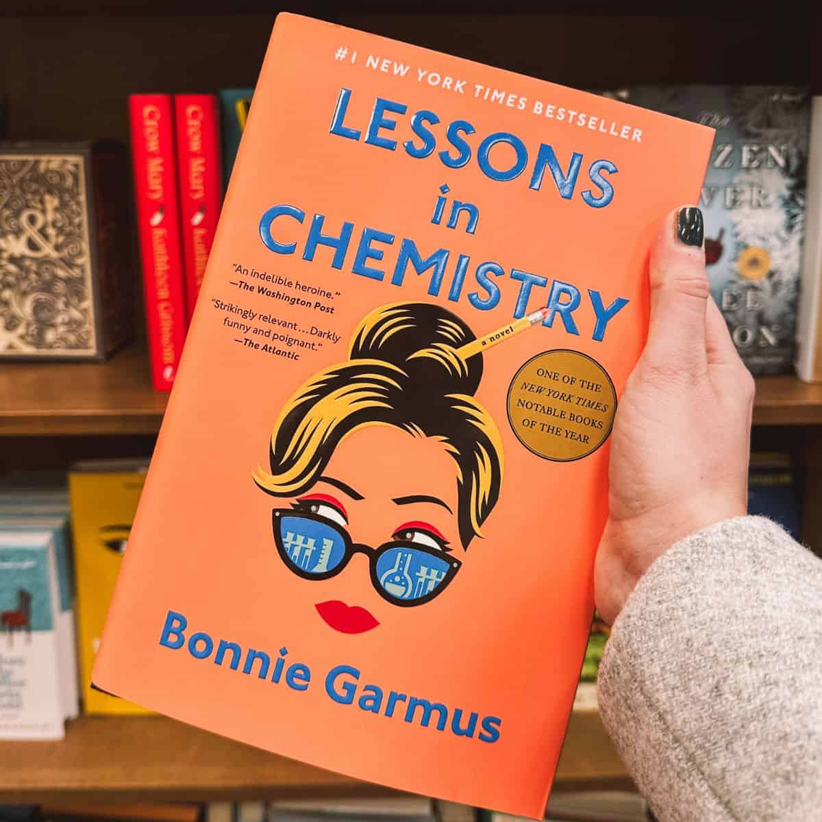 lessons in chemistry by bonnie garmus in front of bookshelves.