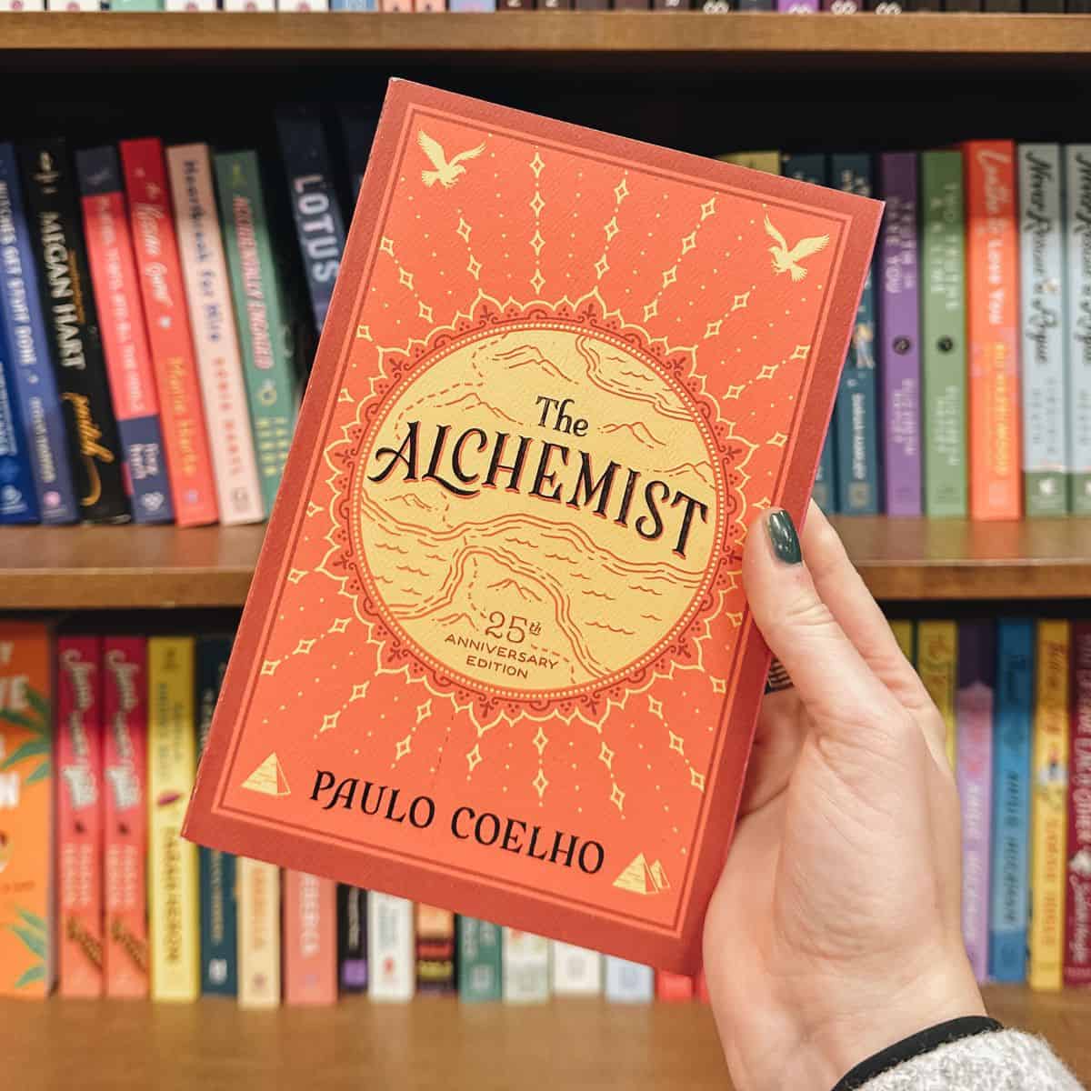 the alchemist by paulo coelho in front of bookshelves.