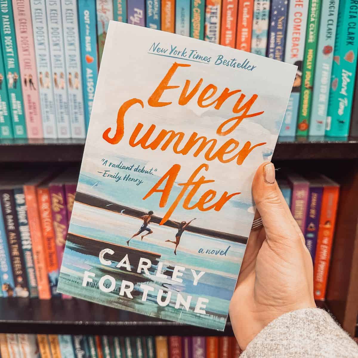 Every summer after by Carley Fortune in front of a bookshelf.