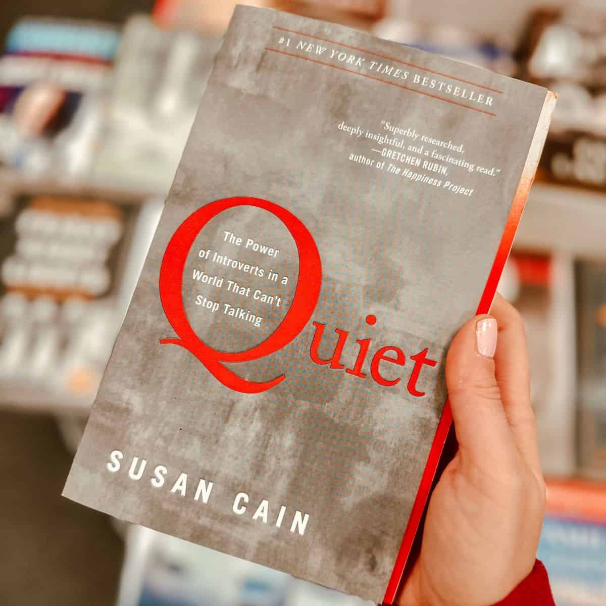 Quiet by Susan Cain held in front of a bookshelf.