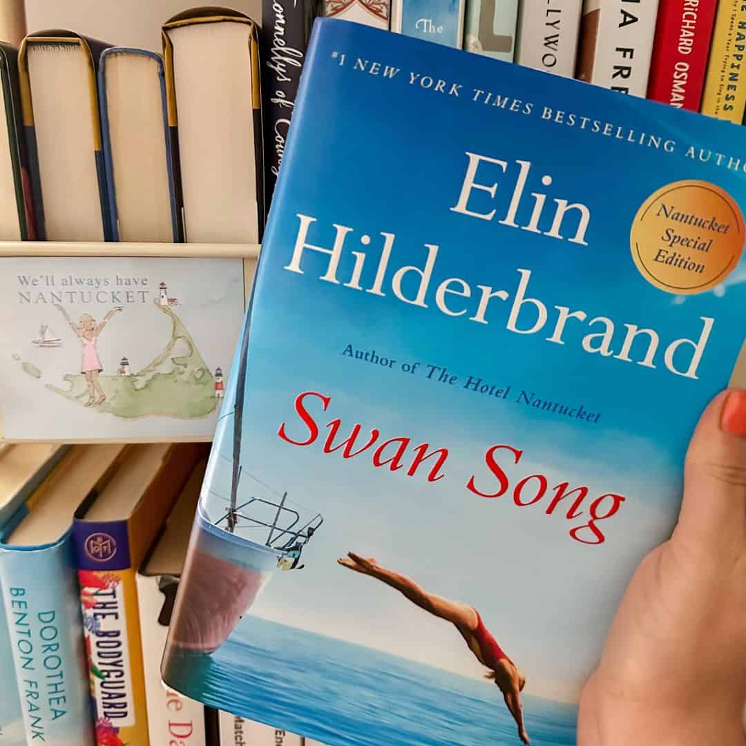 swan song by elin hilderbrand in front of a book cart with a nantucket magnet.