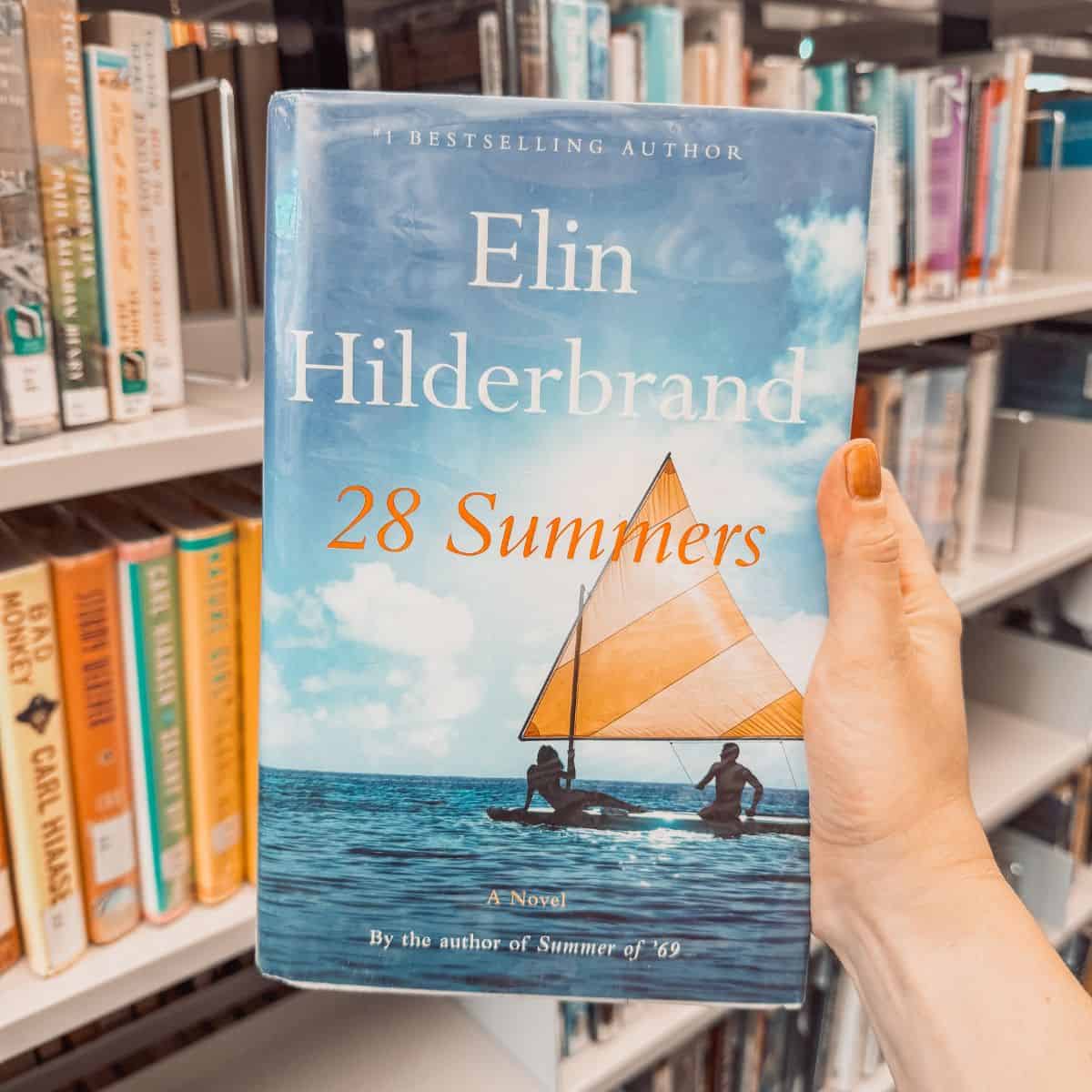 28 summers by elin hilderbrand in front of a bookshelf.