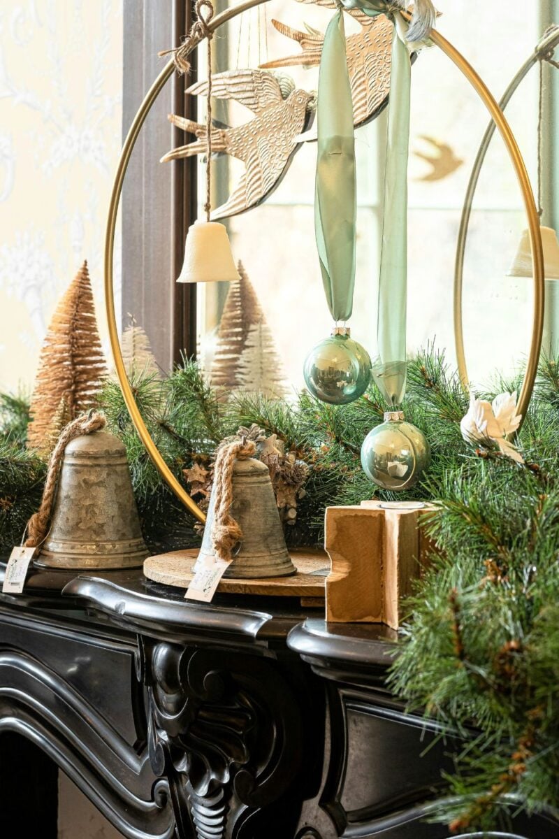 Old fashioned Christmas bells and decorations on a mantle.